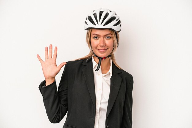 Jeune femme d'affaires caucasienne portant un casque de vélo isolé sur fond blanc souriant joyeux montrant le numéro cinq avec les doigts.