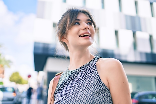 Jeune femme d'affaires caucasienne souriante heureuse marchant dans la ville