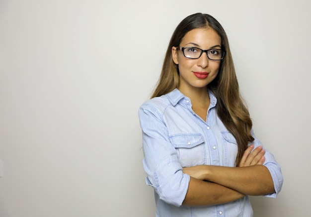 Jeune femme d'affaires en chemise de jeans et lunettes debout avec les bras croisés