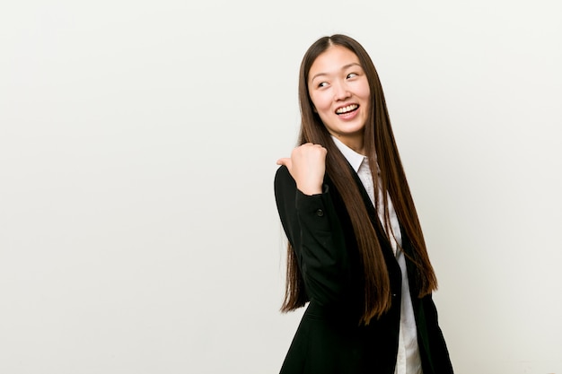 Jeune femme d'affaires chinoise jolie pointe avec le pouce loin, rire et insouciant.