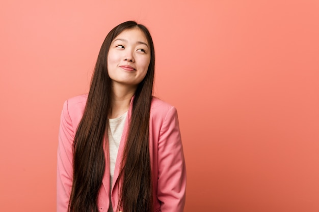 Jeune femme d'affaires chinoise portant un costume rose rêvant d'atteindre les buts et objectifs