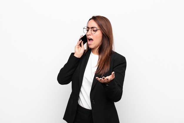 Jeune femme d'affaires à la colère, ennuyé et frustré crier wtf ou quoi de mal avec vous et tenant un téléphone mobile