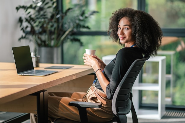 Jeune femme d'affaires confiante au bureau qui a l'air bonne et positive