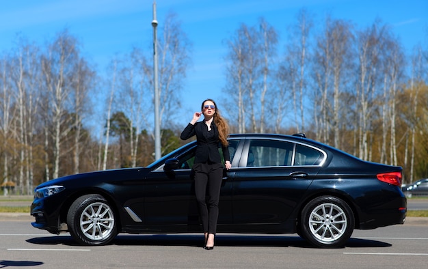 Jeune femme d'affaires à côté de voiture