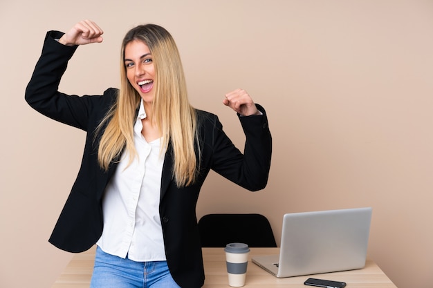 Jeune femme d'affaires dans un bureau célébrant une victoire