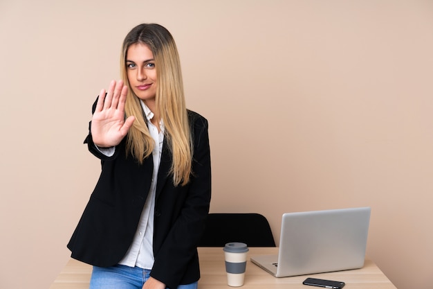 Jeune femme d'affaires dans un bureau faisant un geste d'arrêt avec sa main