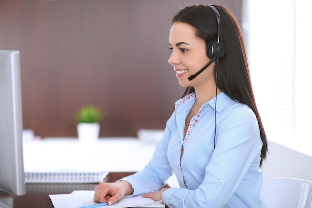 Jeune femme d'affaires dans un casque, assis à la table du bureau.