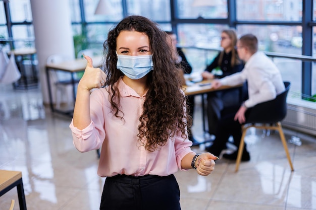 Jeune femme d'affaires dans un masque travaillant au bureau pendant la pandémie de coronavirus