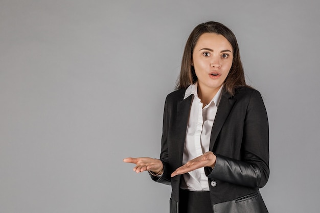 Jeune femme d'affaires dans une suite sombre sur fond gris