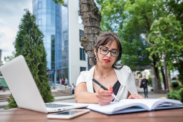 Une jeune femme d'affaires est assise dans un café et travaille avec un ordinateur portable