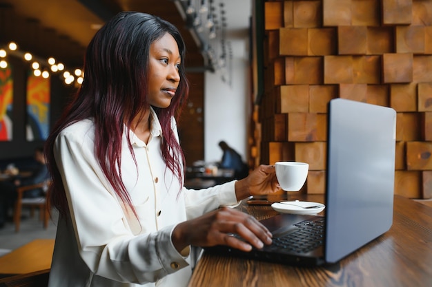 Jeune femme d'affaires ou étudiante afro-américaine concentrée regardant un ordinateur portable femme noire sérieuse travaillant ou étudiant avec un ordinateur faisant des recherches ou se préparant à un examen en ligne