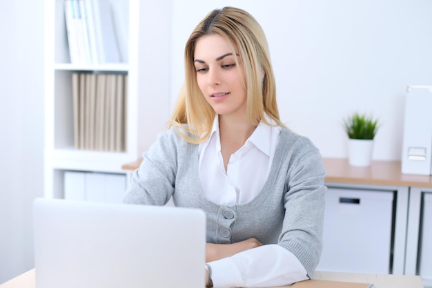 Jeune femme d'affaires ou étudiante assise au bureau avec un ordinateur portable. Concept d'entreprise à domicile.