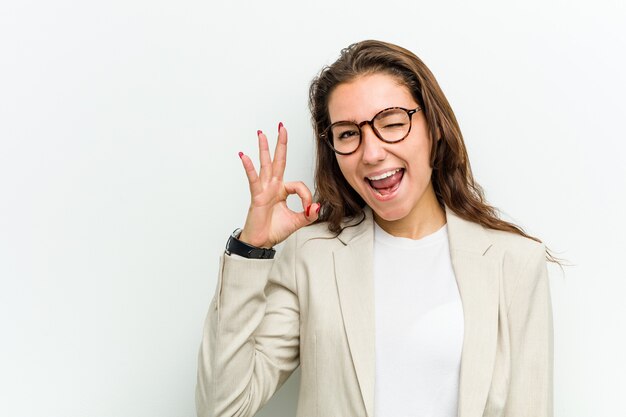 Jeune femme d'affaires européenne fait un clin d'œil et tient un bon geste avec la main.