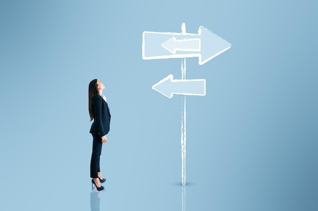 Photo jeune femme d'affaires européenne pensant quel chemin choisir sur fond bleu avec croquis de signe concept de direction différente