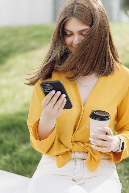 Jeune femme d'affaires faisant défiler le smartphone près de l'espace de bureau femme d'affaires attrayante à l'aide de smart pho