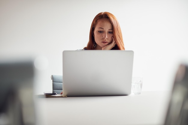 Jeune femme d'affaires habillée avec désinvolture travaillant sur un ordinateur portable au bureau dans un lieu de travail moderne