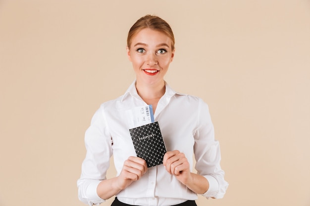 Jeune femme d'affaires heureuse isolée tenant un passeport.