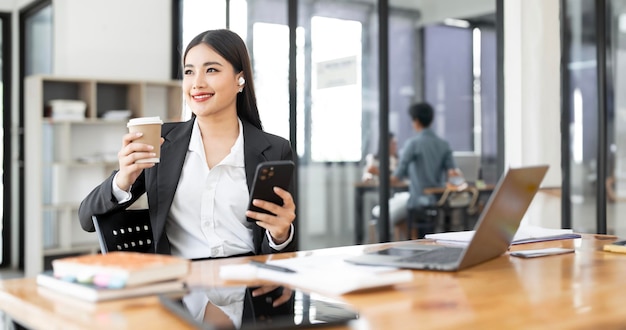 Jeune femme d'affaires heureuse de réussir lors d'une pause-café assise à son bureau levant les yeux avec un sourire de contentement et de plaisir