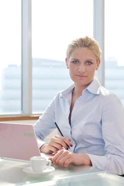 une jeune femme d'affaires heureuse travaillant sur un ordinateur portable lors d'une réunion d'équipe de groupe au bureau moderne