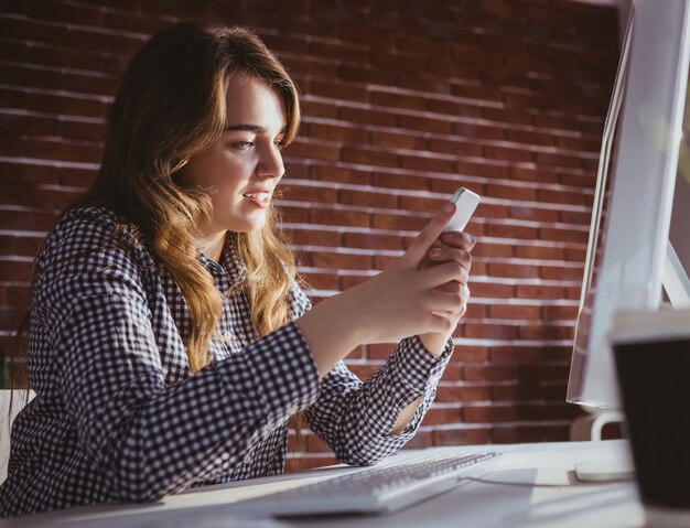 Jeune femme d&#39;affaires hipster utilisant son téléphone à son bureau dans le bureau