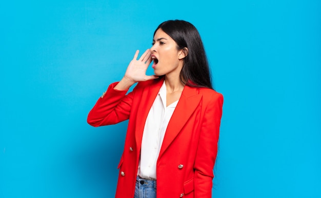 Jeune Femme D'affaires Hispanique Crier Fort Et Avec Colère Pour Copier L'espace Sur Le Côté, Avec La Main à Côté De La Bouche