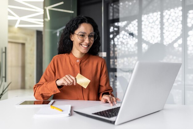 Jeune femme d'affaires hispanique réussie travaillant à l'intérieur du bureau sur le lieu de travail joyeuse ouvrière