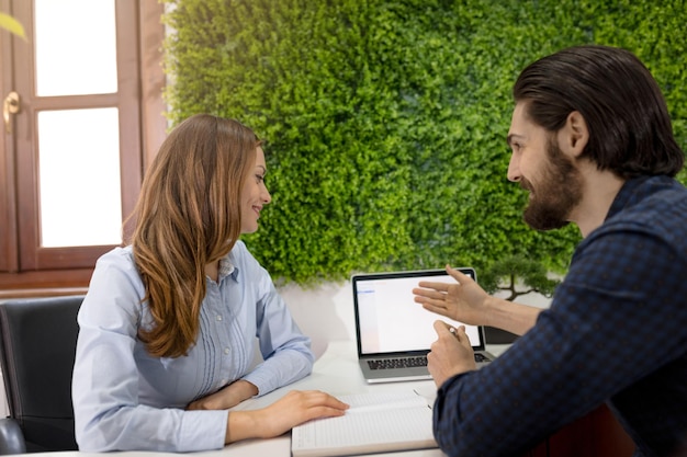 Jeune femme d'affaires et homme d'affaires prospère analysant un projet et en parlant au bureau.