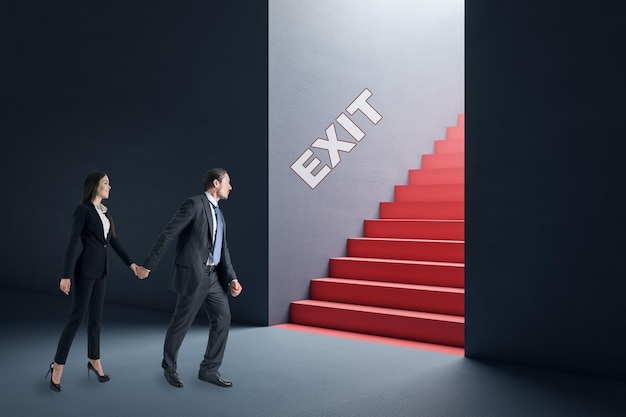 Jeune femme d'affaires et homme réfléchis dans un intérieur en béton regardant la sortie des escaliers rouges Solution de travail d'équipe et concept de choix