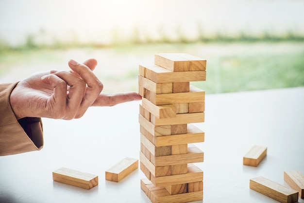 Jeune femme d&#39;affaires intelligente jouant le jeu de bois, les mains en plaçant le bloc de bois