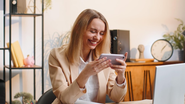 Une jeune femme d'affaires jouant sur un smartphone une application mobile passionnante célèbre le jeu de tir gagnant