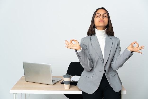 Jeune femme d'affaires latine travaillant dans un bureau isolé sur fond blanc dans une pose zen