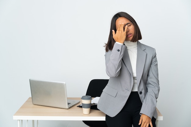 Jeune femme d'affaires latine travaillant dans un bureau isolé sur fond blanc avec des maux de tête