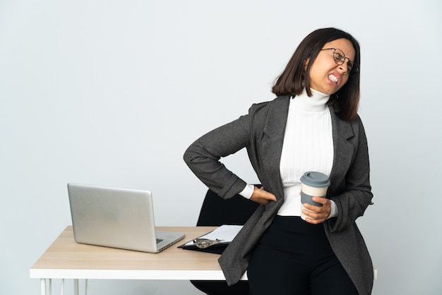 Jeune femme d'affaires latine travaillant dans un bureau isolé sur fond blanc souffrant de maux de dos pour avoir fait un effort