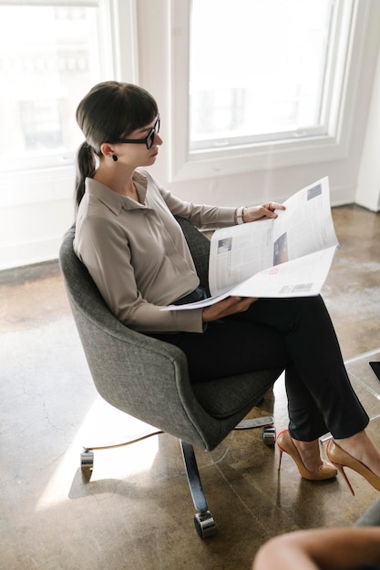 Jeune femme d'affaires lisant un journal