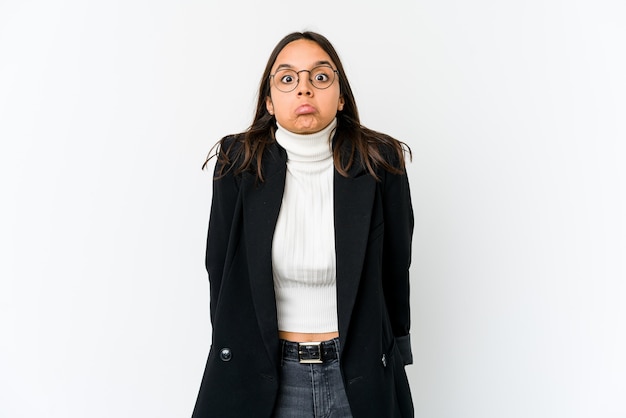 Jeune femme d'affaires métisse isolée sur fond blanc hausse les épaules et les yeux ouverts confus.