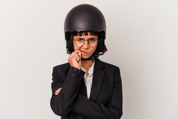 Jeune femme d'affaires métisse portant un casque de moto isolé avec les doigts sur les lèvres gardant un secret.