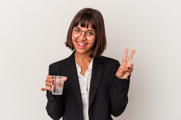 Jeune femme d'affaires métisse tenant un verre d'eau isolé sur fond blanc montrant le numéro deux avec les doigts.