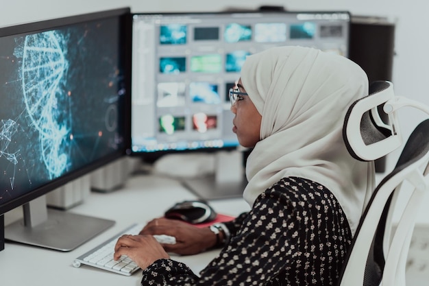 Jeune femme d'affaires musulmane moderne afro-américaine portant un foulard dans un lieu de travail créatif et lumineux avec un grand écran. Photo de haute qualité