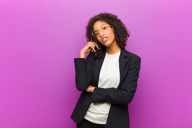 Photo jeune femme d'affaires noire au regard concentré, s'interrogeant avec une expression douteuse, levant les yeux et sur le côté