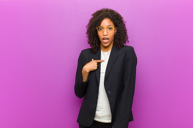 Photo jeune femme d'affaires noire à la recherche de choqué et surpris avec la bouche grande ouverte, pointant vers soi