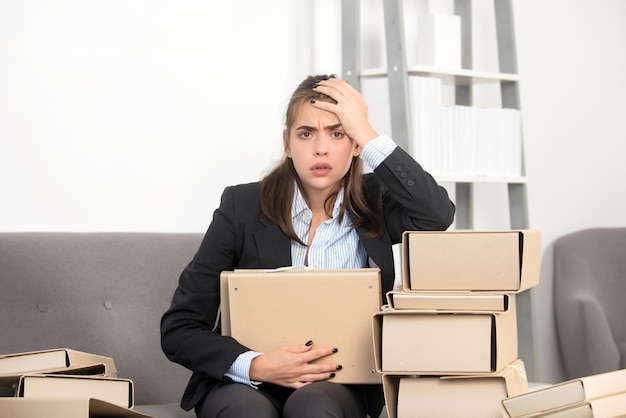 Jeune femme d'affaires occupée avec de nombreux dossiers de documents frustration secrétaire fille faisant des heures supplémentaires