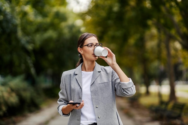 Une jeune femme d'affaires occupée a pris une pause-café dans un parc