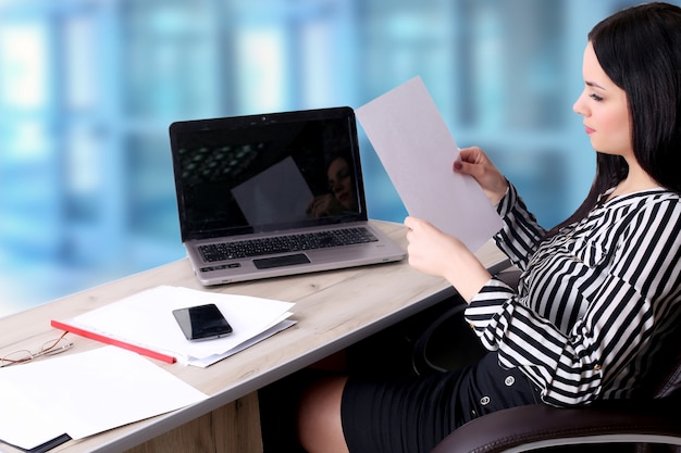 Jeune femme d'affaires avec ordinateur portable au bureau