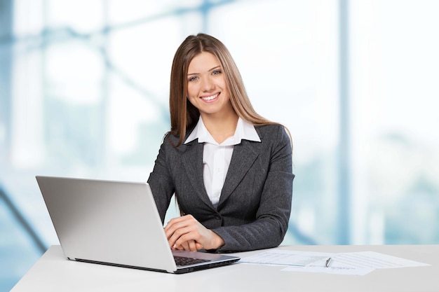 Jeune femme d'affaires avec ordinateur portable souriant à la caméra