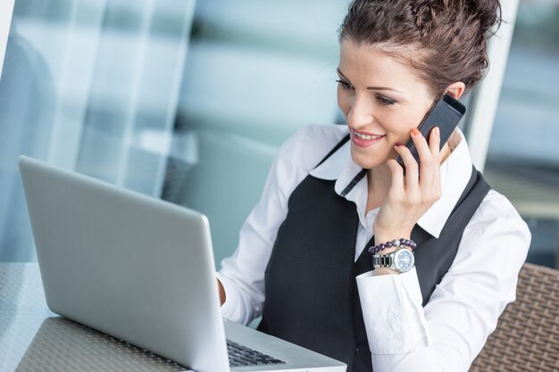 Jeune femme d&#39;affaires avec ordinateur et téléphone portable