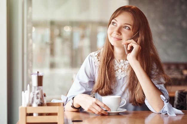 Jeune femme d'affaires parlant au téléphone dans un café.