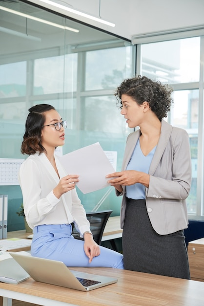 Jeune femme d'affaires passant un rapport avec des données de vente et de marketing à son collègue