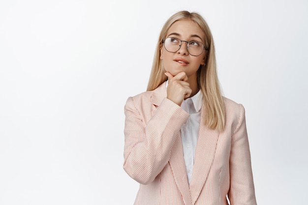 Jeune femme d'affaires pensant, pensant au coin gauche d'upepr, faisant le choix, debout sur blanc