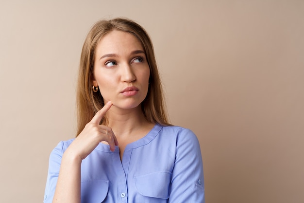 Jeune femme d'affaires pensive pensant à une idée sur fond beige