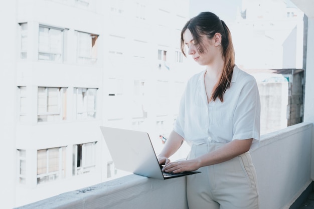 Jeune femme d'affaires pigiste à l'aide d'un ordinateur portable pour travailler à l'extérieur sur un balcon Freelance travail vacances gens d'affaires technologies étude à distance elearning style de vie réunion en ligne